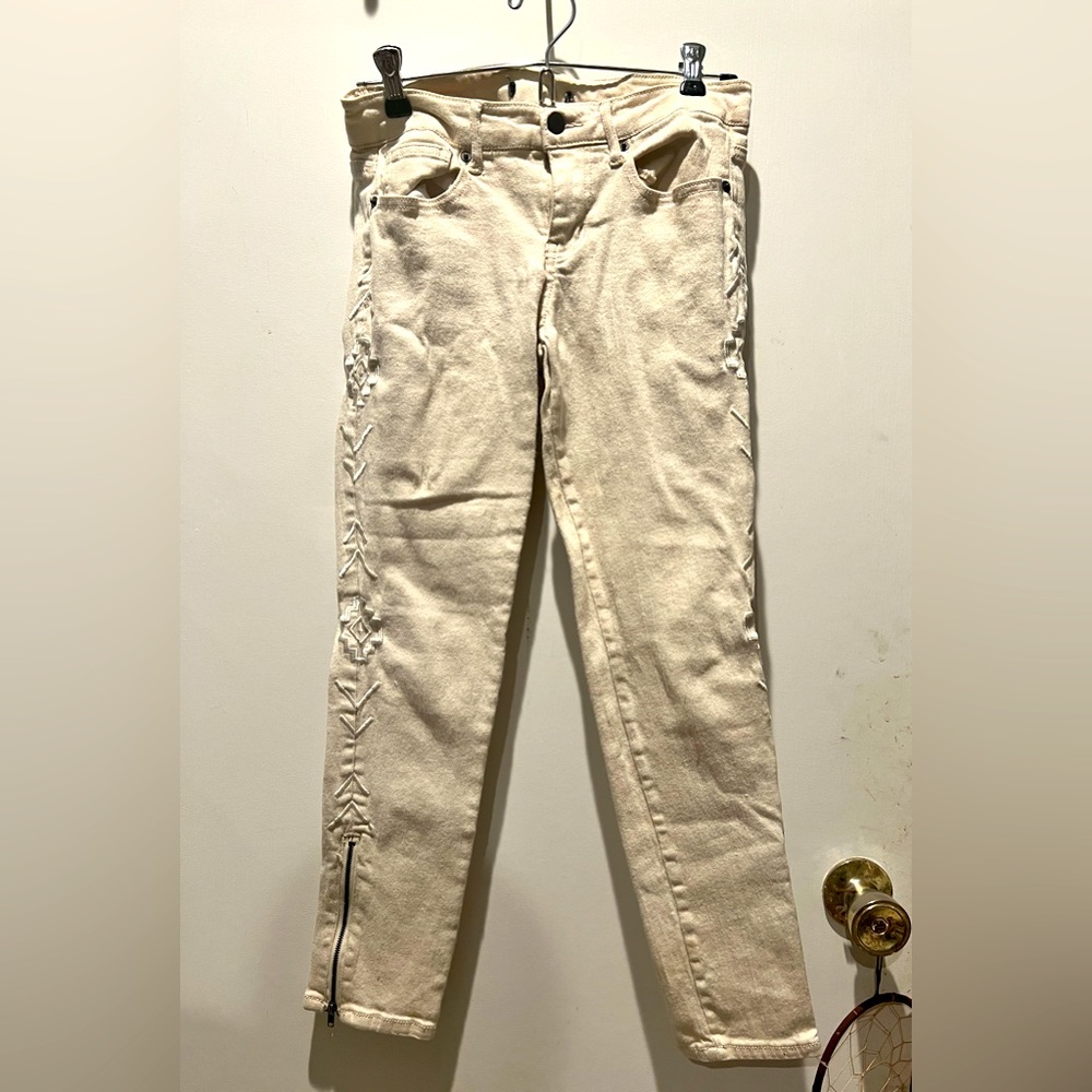 Off-white jeans with tribal print along each side and small zipper by each ankle